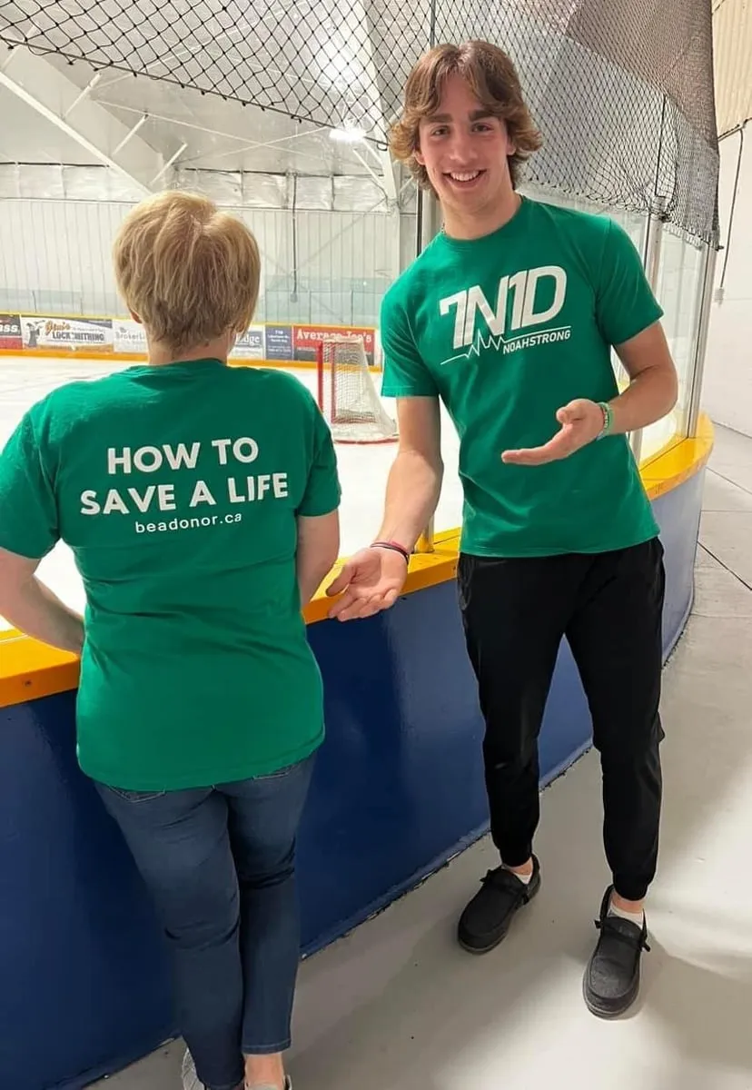 Supporters at a rink in green shirts reading How to save a life
