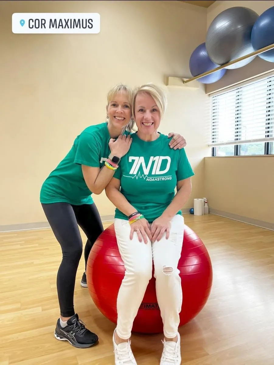 Two women in green 7N1D shirts at a fitness studio
