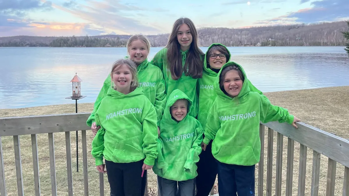 Kids in green NoahStrong hoodies by a lake