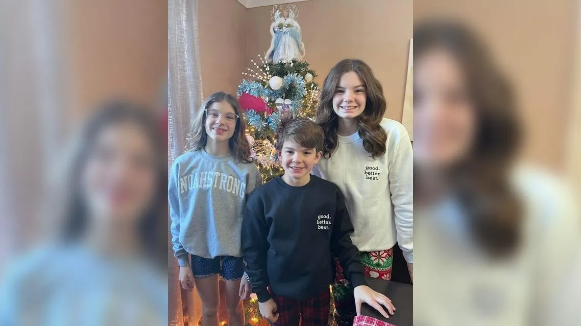 Three kids in NoahStrong sweaters by a Christmas tree