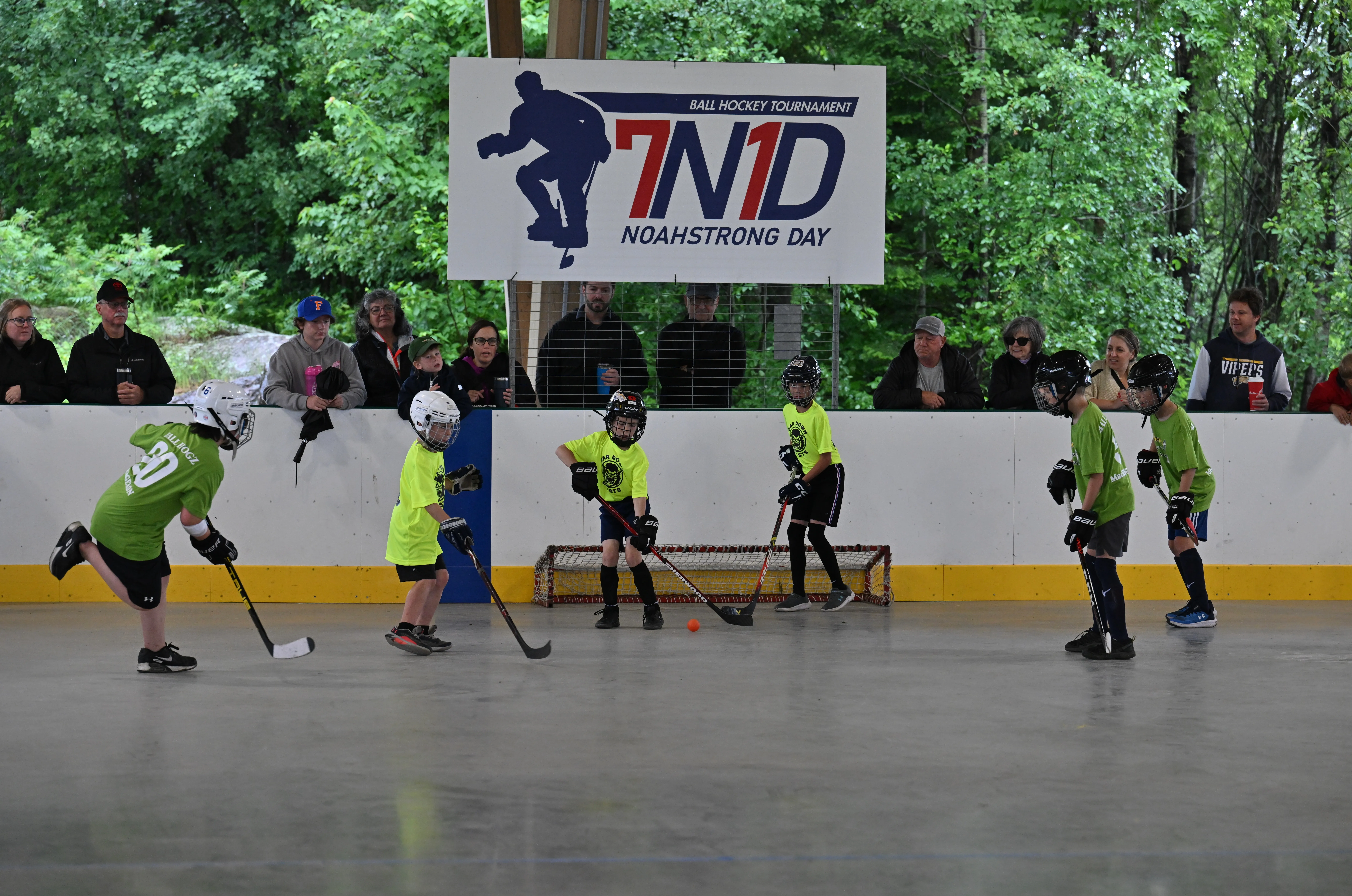 Young players on the floor beneath the 7N1D NoahStrong Day ball hockey tournament banner